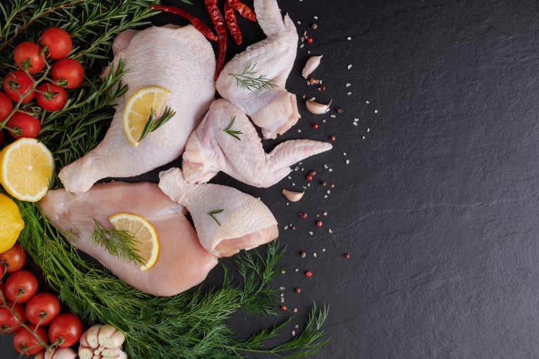 raw chicken fillet with garlic, pepper and rosemary on wooden on